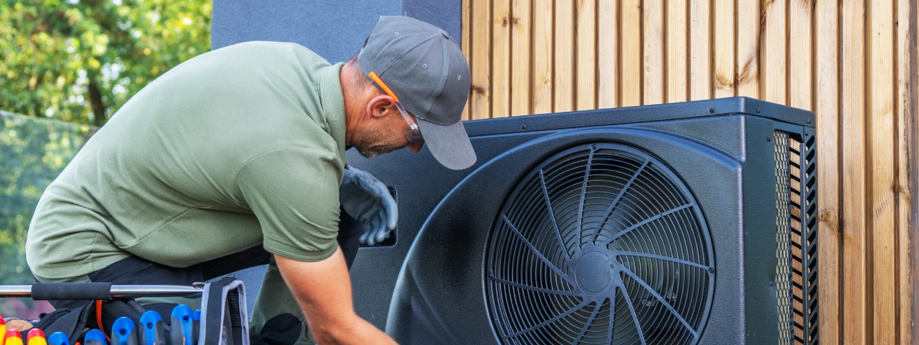 HVAC technician performing maintenance on outdoor air conditioning unit